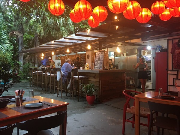 Colorful lights hang over Doki Sushi's outdoor dining area with the sushi bar in the background.
