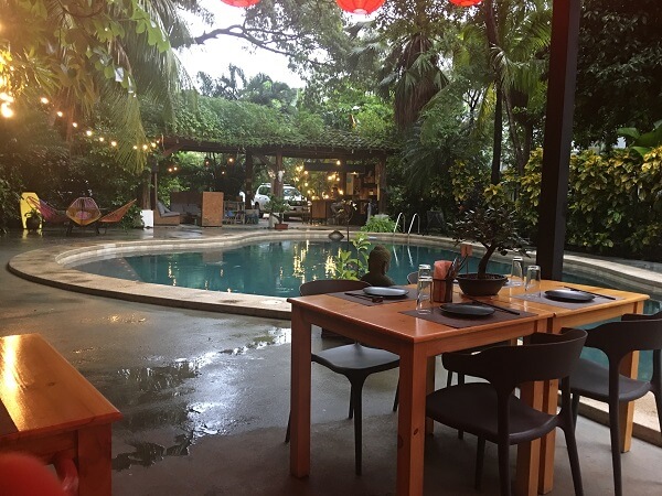 Covered dining area next to the pool area and tropical garden.