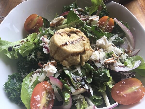 The Summer Salad with tomatoes, onions, cranberries and a twice baked goat cheese souffle on top.