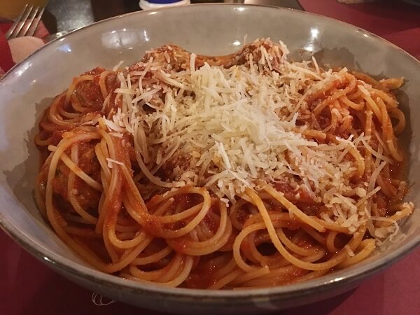 Large bowl of perfectly prepared spaghetti and meatballs with a tomato sauce topped with parmesan cheese.