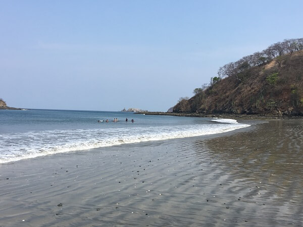A group of swimmers enjoying the warm water and small surf at Playa Penca.