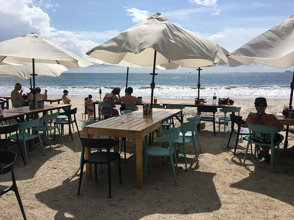 Tables set up in the sand facing the ocean at Coco Loco in Playa Flamingo Costa Rica.