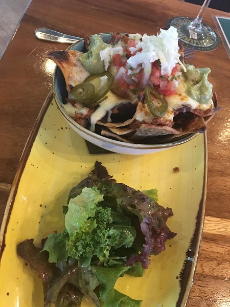 Nachos with BBQ chicken, jalapenos, pico de gallo, mozzarella cheese, black beans, red cabbage with salsa, sour cream and guacamole.