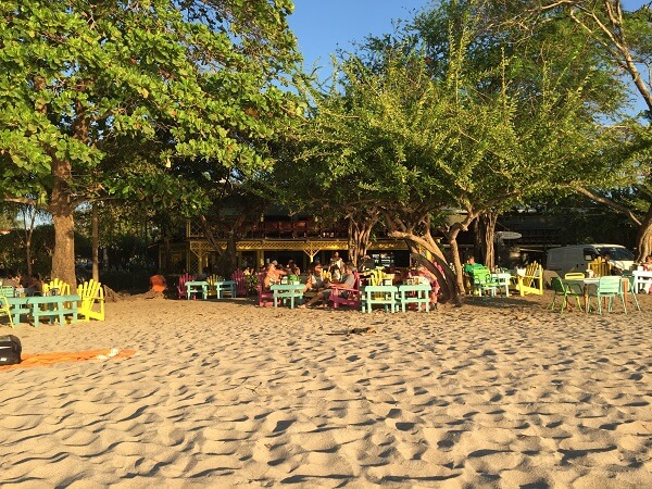 Tables and chairs in the sand right next to the water at the Pacifico bar in Tamarindo
