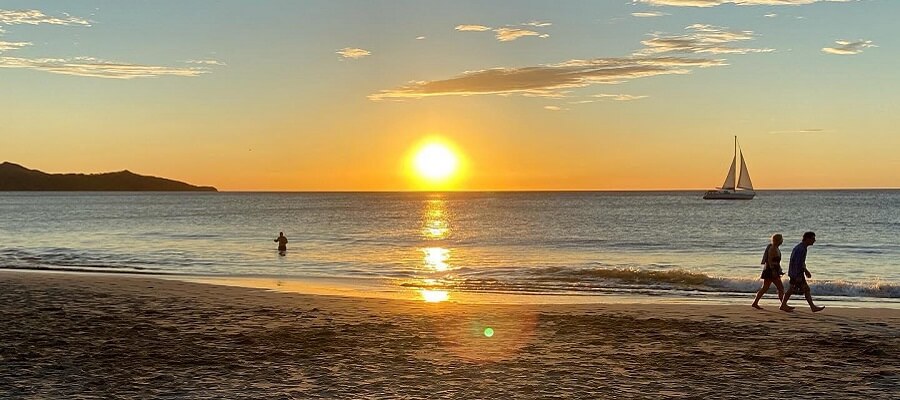 Sun sets next to sailboat in Playa Flamingo Costa Rica.