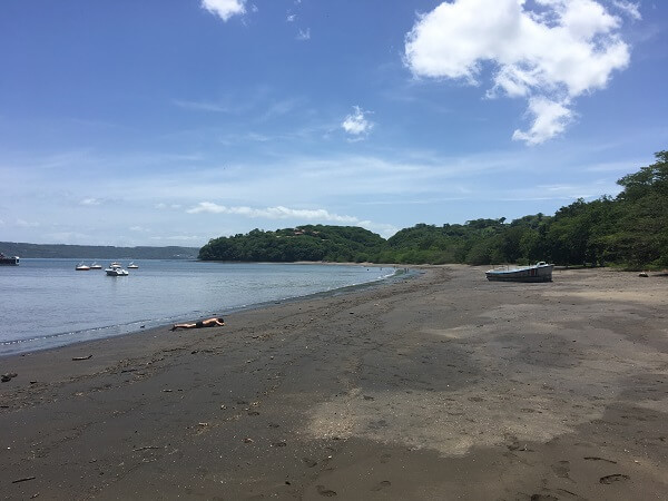 View of Playa Panama, with its dark colored sand at low tide, looking north towards at the Gulf of Papagayo.